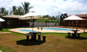 two tables with umbrellas next to a swimming pool at Pousada Maresia do Sargi in Uruçuca +14 photos