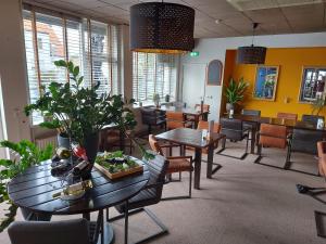 a dining room with tables and chairs and plants at Hotel de Zwaan in Schoondijke