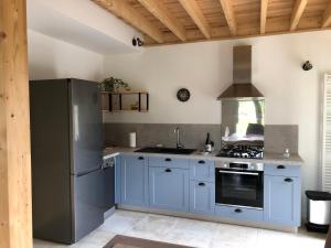 a kitchen with blue cabinets and a stainless steel refrigerator at Gite 4 places, le Domaine de la Vallée in Saint-Martin-de-Varreville +23 photos