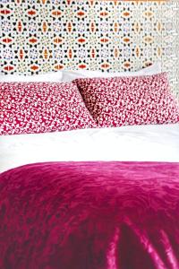 a bed with red and white pillows on it at Hotel Andalou in Montellano