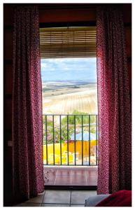 a window with red curtains and a view of a field at Hotel Andalou in Montellano