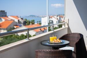 un vaso de zumo de naranja y un plato de comida en una mesa en un balcón en Seaside vila Perla en Podstrana