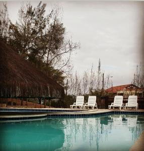drei weiße Stühle neben einem Pool in der Unterkunft Apart Hotel Fazenda Monte Castelo - Gravatá in Gravatá