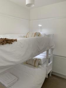uma cama branca com lençóis e almofadas brancos em 'Sandy Bottom' Broadstairs by the beach em Broadstairs