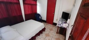 Dormitorio pequeño con cama y TV en Tropical Dreams Hostel en Corn Island