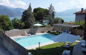 a house with a swimming pool and an umbrella at Akuaduulza B&B Como Lake in San Siro