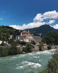 Blick auf einen Fluss mit einer Stadt im Hintergrund in der Unterkunft Rosa's Boutique Apartment & parking in Meran