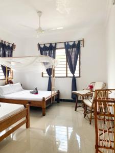 a bedroom with two beds and a table and chairs at Lighthouse Guesthouse in Nungwi