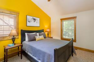 ein Schlafzimmer mit gelben Wänden, einem Bett und zwei Fenstern in der Unterkunft Blue Spruce . Trailside Lodging in Millersburg