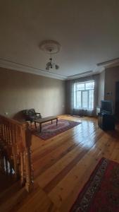 an empty living room with a table on a wooden floor at Дом в Хырдалане in Xirdalan
