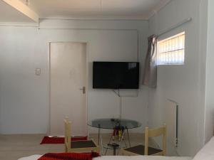 uma sala de estar com uma mesa e uma televisão na parede em Gold Reef Hideout em Joanesburgo