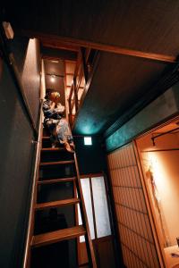 une personne est assise sur une échelle dans une pièce dans l'établissement Machiya Kikunoya Hanare, à Nagoya