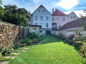 a yard of a white house with a stone wall at Penzion SECESE in Telč