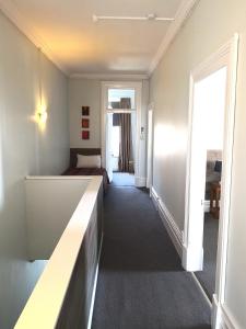 a corridor of a room with a bed and a desk at Owens Motel in Dunedin
