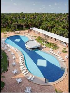 a large swimming pool with chairs and a building at Gran Lençóis Flat Apartamento in Barreirinhas