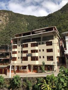 a large white building with a mountain in the background at Casa De Luz Hotel in Machu Picchu