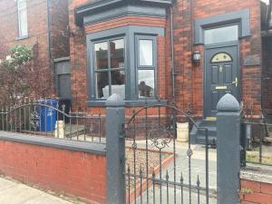 een huis met een zwarte deur en een hek bij Quigley Buildings - Stylish Entire 2 bed House sleeps 5 Wigan - Private Garden - Free parking - Wifi - Secure garden in Pemberton