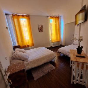 a bedroom with two beds and yellow curtains at LE COMMERCE in Pont-sur-Yonne