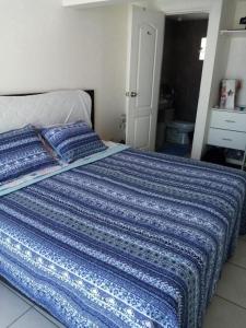 Una cama con una manta azul encima. en El Refugio, en Punta Hermosa