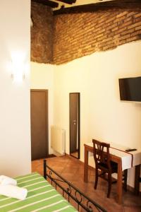 ローマにあるSixtythree guesthouseのベッド、デスク、テレビが備わる客室です。