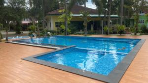 a large swimming pool with blue water in front of a house at Somrudee Resort in Nakhon Nayok