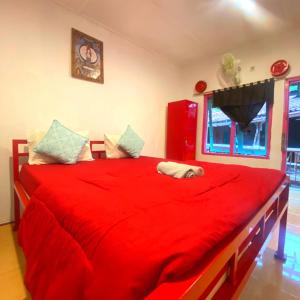a bedroom with a red bed with a red blanket at La Boheme Bajo in Labuan Bajo