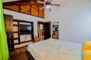 a bedroom with a bed and a flat screen tv at Casa Shaquir H - Coastal Bliss Oasis in Puerto Viejo