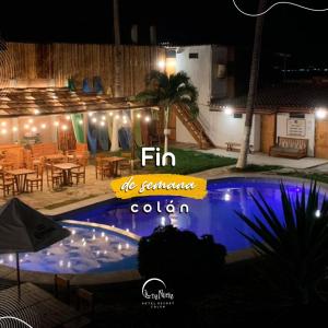 a swimming pool at night with a table and chairs at Hotel Luna Nueva in Colán