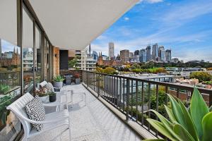 uma varanda com cadeiras brancas e vista para a cidade em Inner City Harbour Views With Parking em Sidney