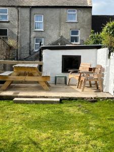 una mesa de picnic y dos bancos en un patio en Driftwood House, en Portaferry