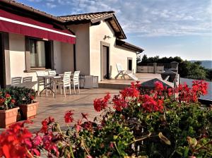 a house with a deck with red flowers at Agriturismo PIAN DEL GRANO Azienda agricola in Grotte di Castro