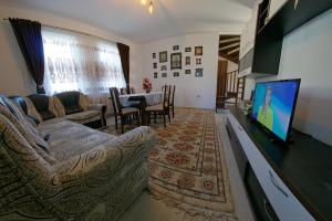 ein Wohnzimmer mit einem Sofa und einem Flachbild-TV in der Unterkunft La Roata Timpului in Câmpulung Moldovenesc