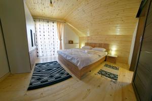 ein Schlafzimmer mit einem Bett in einem Holzzimmer in der Unterkunft La Roata Timpului in Câmpulung Moldovenesc