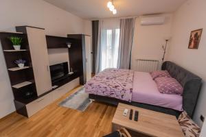 een kleine slaapkamer met een bed en een televisie bij Elite One Premium Apartment in Sarajevo