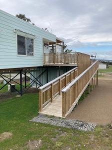 a house with a wooden deck next to a building at Bruny Ocean Cottage in Alonnah