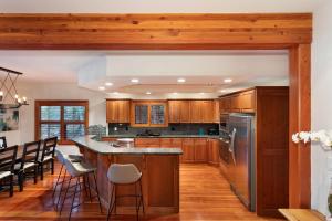 a kitchen with wooden cabinets and a island with bar stools at Luxury 5 Bedroom Blueberry Chalet in Whistler