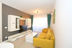 a living room with a yellow couch and a tv at Apartament Prima Nufarul Ralu in Oradea