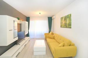 a living room with a yellow couch and a tv at Apartament Prima Nufarul Ralu in Oradea
