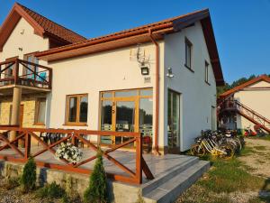 a house with a wooden deck in front of it at Chill Out Wygryny in Ruciane-Nida