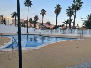 una piscina con palmeras y sombrillas en Velilla Park 2 Playa, en Almuñécar