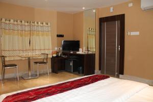 a bedroom with a bed and a desk and a television at Shreekrishna Hotels & Resorts Pvt Ltd in Kolkata +12 photos