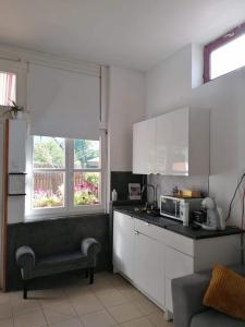 a kitchen with white cabinets and a microwave oven at Plum13 in Szolnok