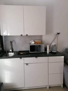 a kitchen with white cabinets and a microwave on a counter at Plum13 in Szolnok