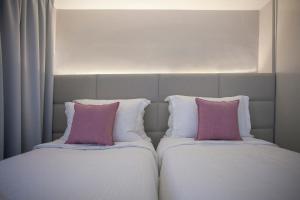 2 letti con cuscini rosa, posti uno accanto all'altro di Aquarius Boutique Hotel a Rethymno