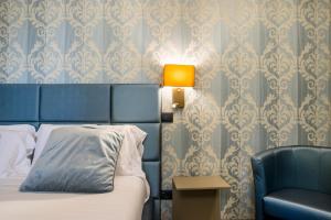 a bedroom with a bed and a lamp and a chair at Via Veneto Suites in Rome