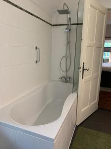 a white bath tub in a bathroom with a shower at Bed and Breakfast Goes in Goes