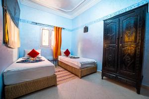 1 dormitorio con 2 camas y un gran armario de madera en Original Surf Morocco, en Tamraght Ouzdar