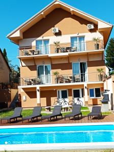 ein Gebäude mit Stühlen und einem Pool davor in der Unterkunft Karos Bianco Apartmanház in Zalakaros