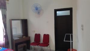 Cette chambre comprend deux chaises rouges, un bureau et un miroir. dans l'établissement DARRA HOMESTAY TORAJA, à Rantepao