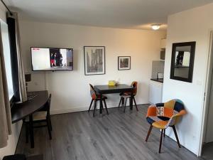 sala de estar con mesa, sillas y TV en Le Saint Martin du Touch Fitness & Business, en Toulouse